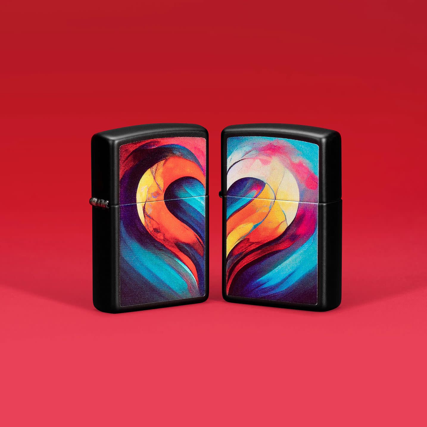 Lifestyle image of two Zippo Whole Heart Set Design Black Matte Windproof Lighters standing on a red background.