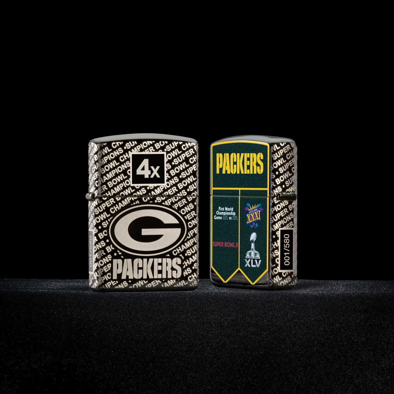 Glamour shot of two Zippo NFL Green Bay Packers Super Bowl Commemorative Armor Black Ice Windproof Lighters in a black scene, one lighter showing the front and the other showing the back.