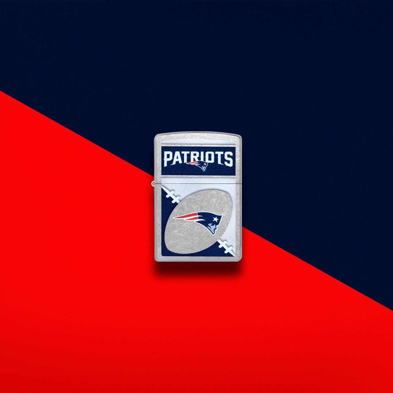 Lifestyle image of Zippo NFL New England Patriots Street Chrome Windproof Lighter set on a red and dark blue background.