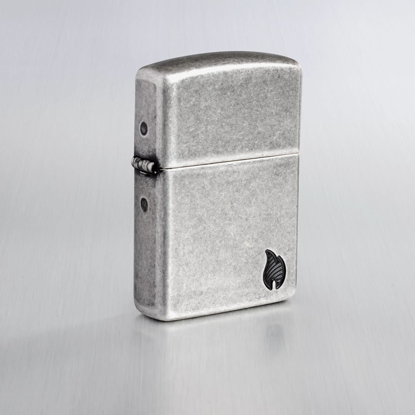 Lifestyle image of Zippo Armor® Series Flame Antique Silver Windproof Lighter on a light gray background.