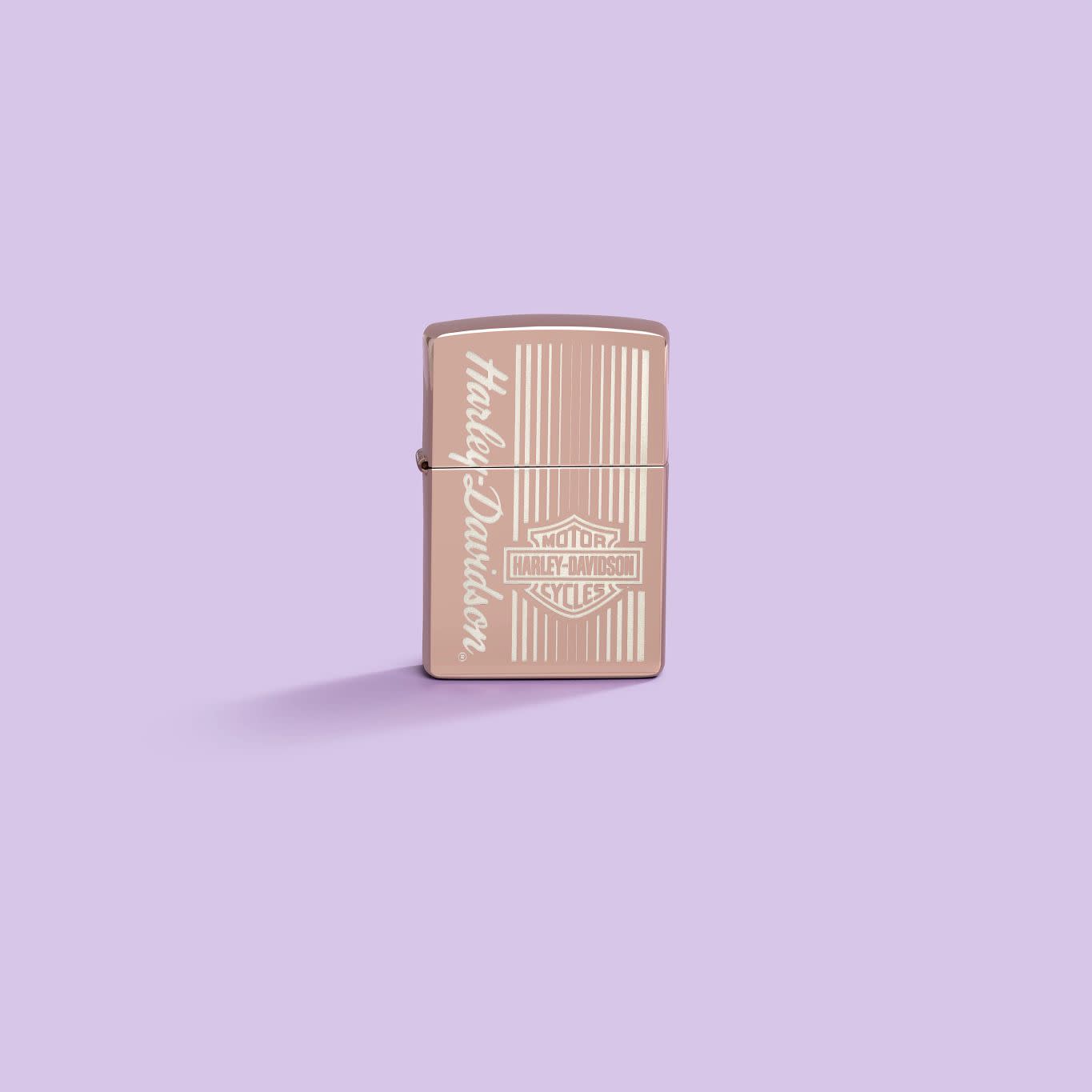 Lifestyle image of Zippo Harley-Davidson® High Polish Rose Gold Windproof Lighter on a pastel purple background.