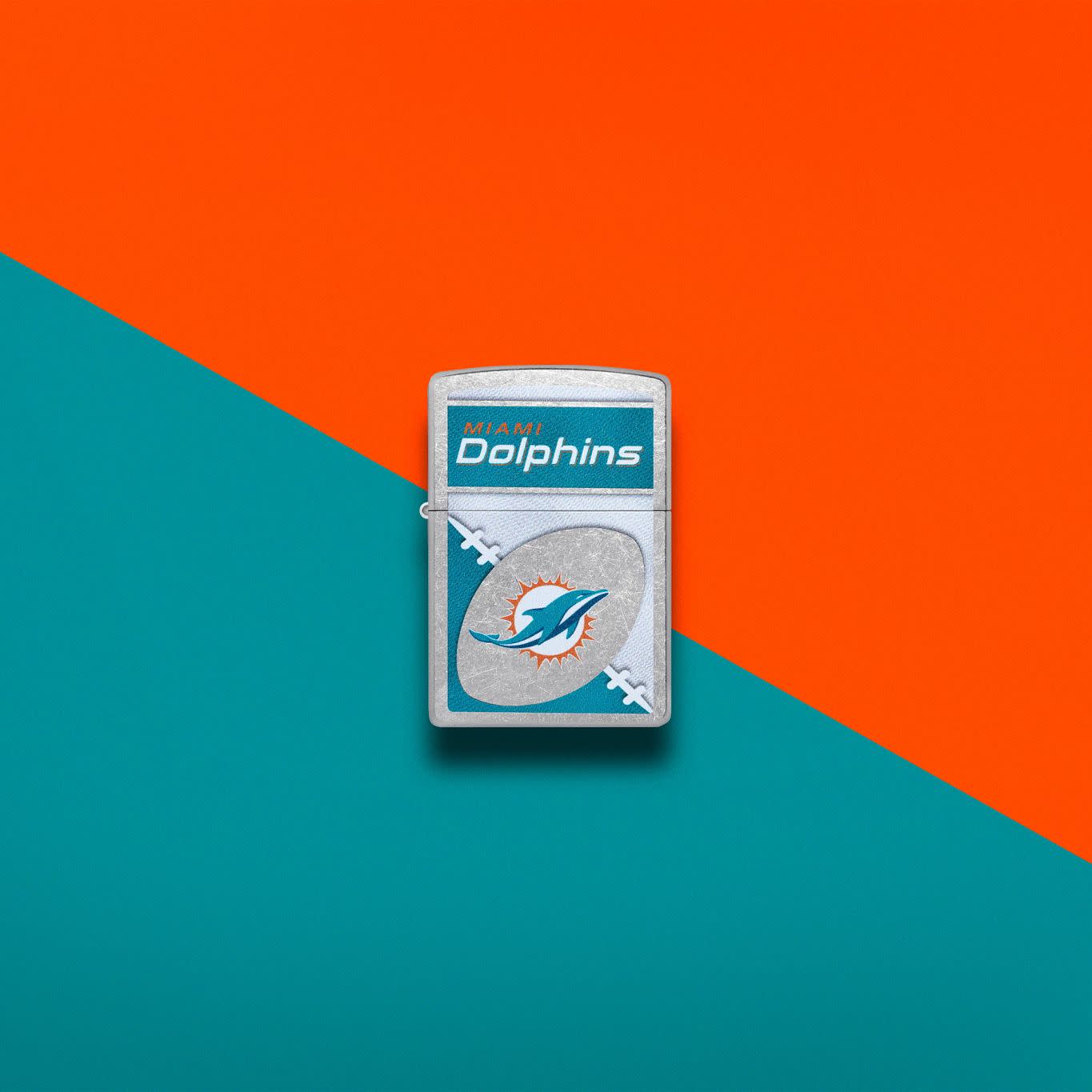 Lifestyle image of Zippo NFL Miami Dolphins Street Chrome Windproof Lighter set on an orange and teal background.