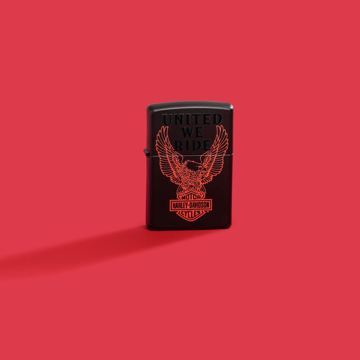 Lifestyle image of Zippo Harley-Davidson® Black Matte Windproof Lighter on a red background.