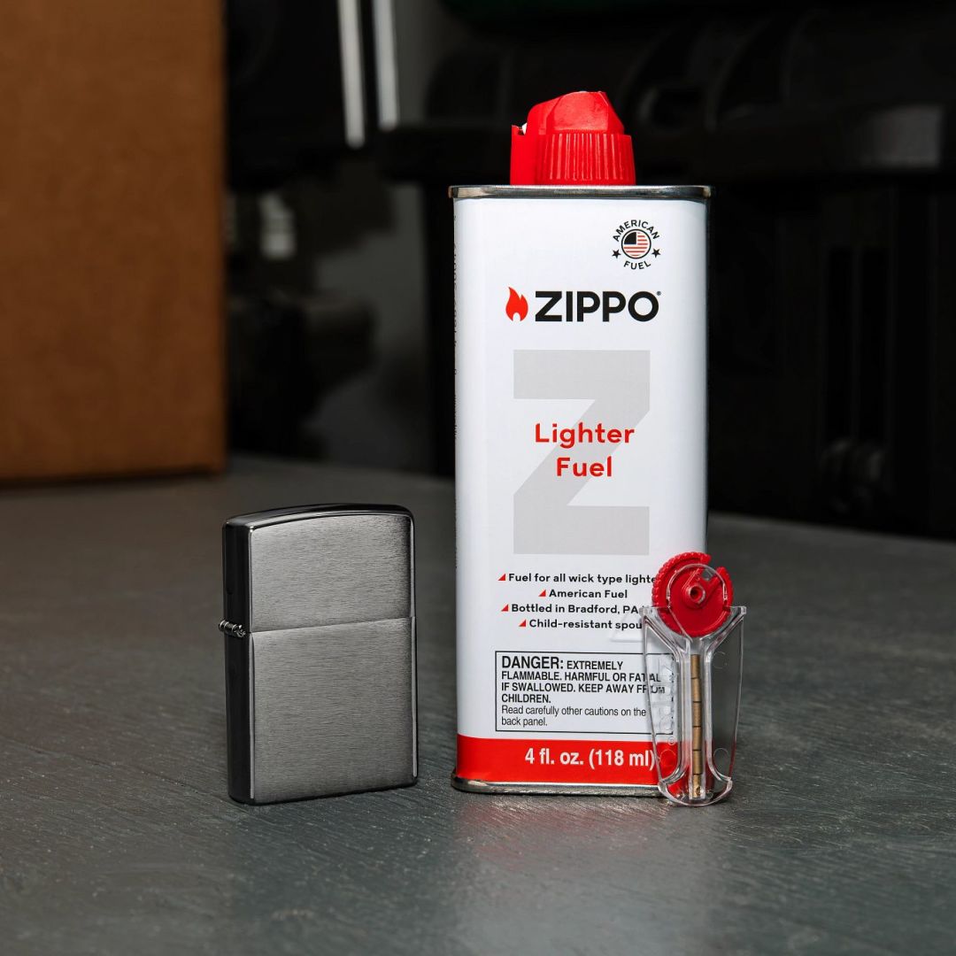 Lifestyle image of Zippo All-In-One Gift Set with Classic Brushed Chrome Windproof Lighter standing on a table showing the lighter, fuel and flint dispenser

