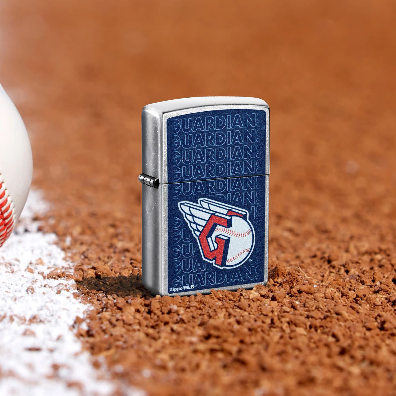 Lifestyle image of Zippo MLB® Cleveland Guardians Street Chrome Windproof Lighter standing in the dirt on a baseball field.