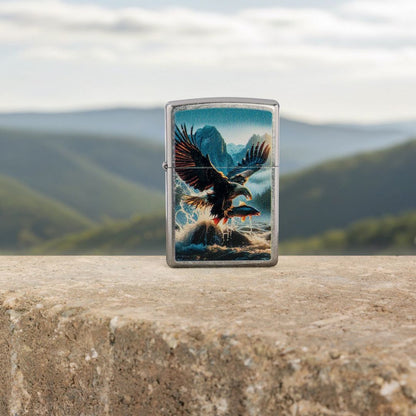 Lifestyle image of Zippo Catch of the Day Design Street Chrome Windproof Lighter standing on the ledge of a concrete structure showing the front of the lighter with an out of focus scenic background with green mountains. 

