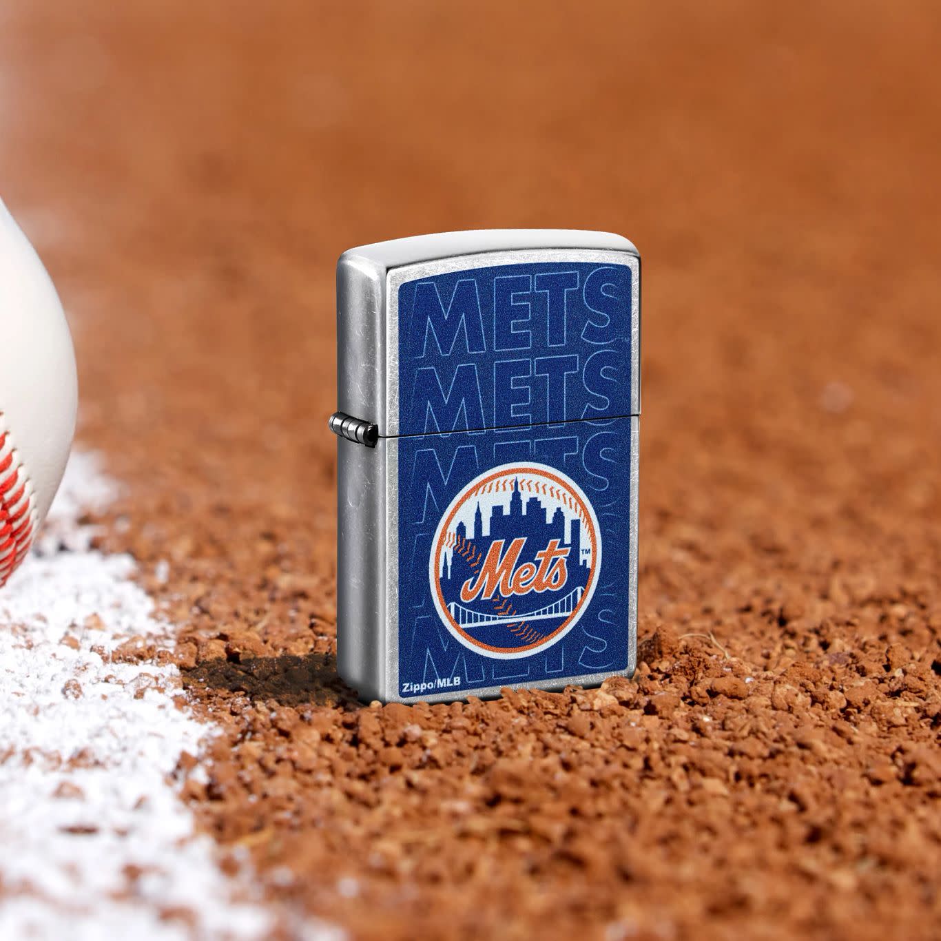 Lifestyle image of Zippo MLB® New York Mets Street Chrome Windproof Lighter standing in the dirt on a baseball field.