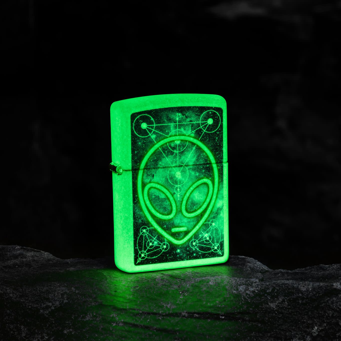 Lifestyle image of Zippo Glowing Alien Design Glow in the Dark Windproof Lighter glowing in the dark.