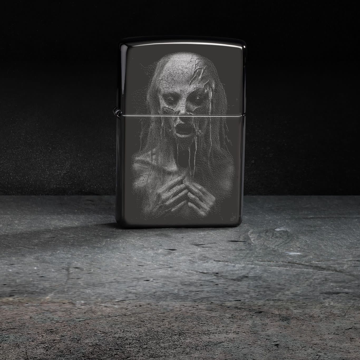 Lifestyle image of Zippo Monster Design High Polish Black Windproof Lighter standing on a gray surface with black background.