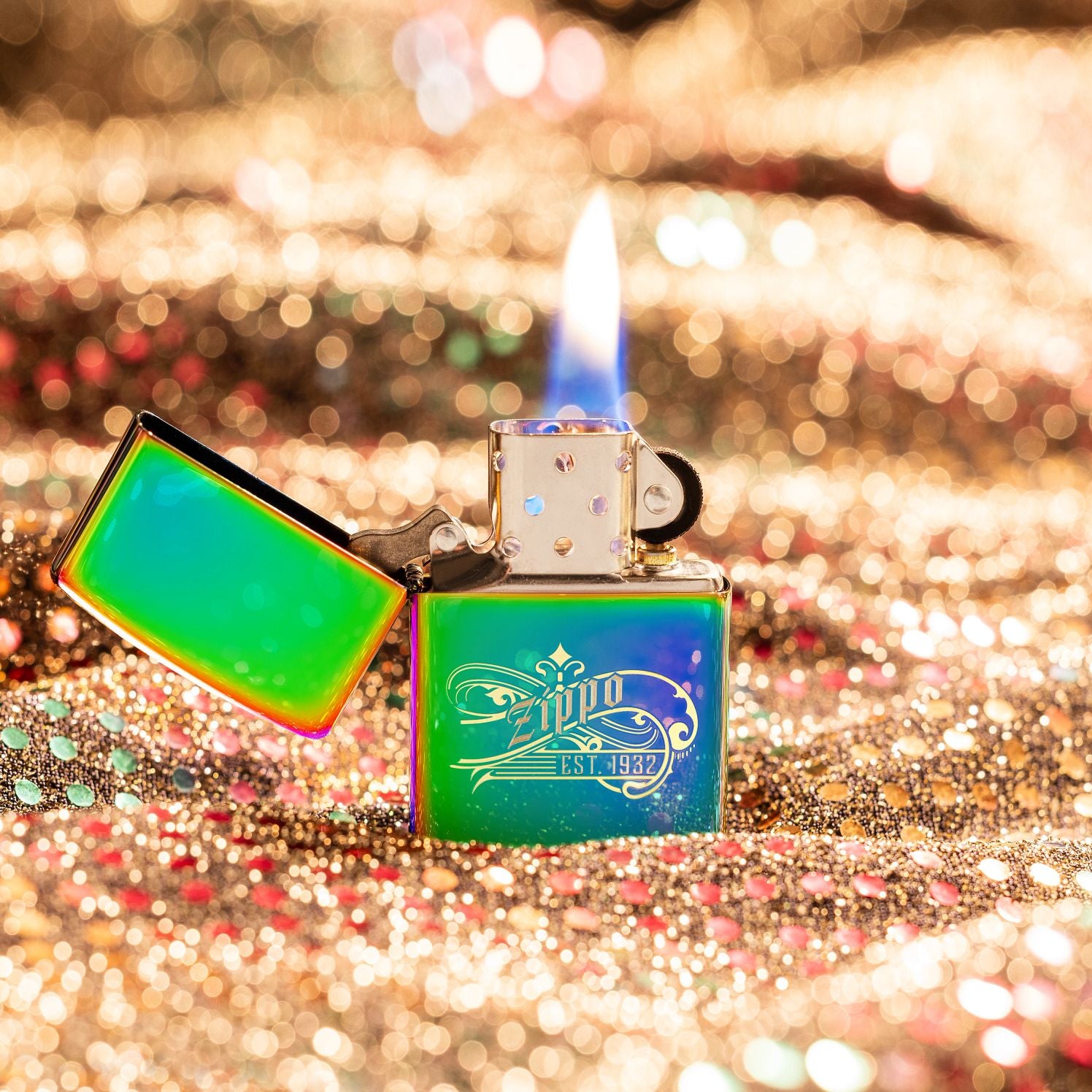 Lifestyle image of Zippo Established 1932 Design Multi Color Windproof Lighter standing with a gold glitter background. 

