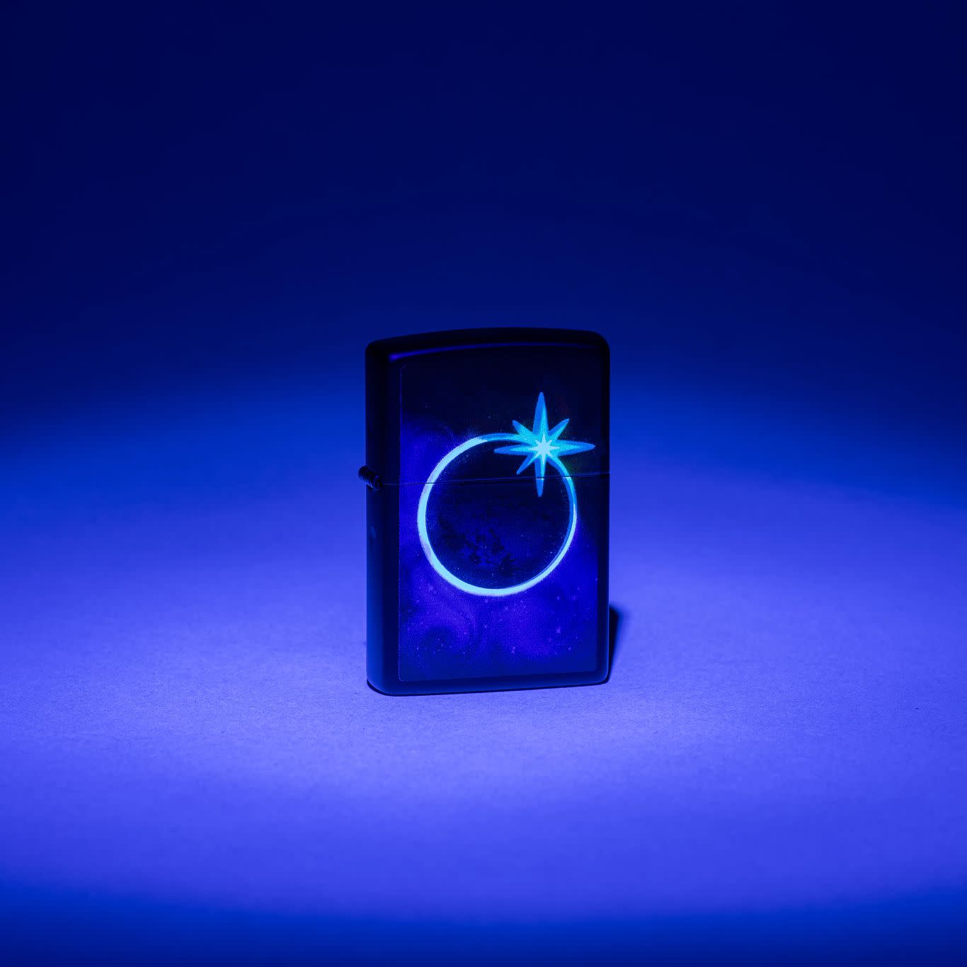 Lifestyle image of Zippo Eclipse Design Black Matte Windproof Lighter glowing under a black light.