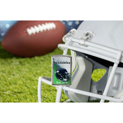 Lifestyle image of Zippo NFL Seattle Seahawks Helmet Design Street Chrome Windproof Lighter standing on the facemask of a white helmet showing the front of the lighter with a football lying on a football field as the background.

