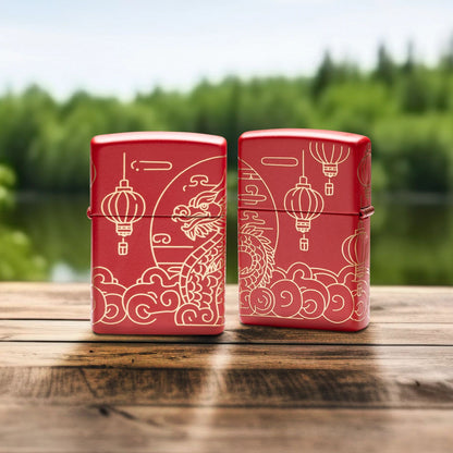 Lifestyle image of two Zippo Chinese New Year Design Red Matte Windproof Lighters standing on a wooden railing with a creek and green trees as the background; one showing the front of the lighter, while the other is showing the back of the lighter. 