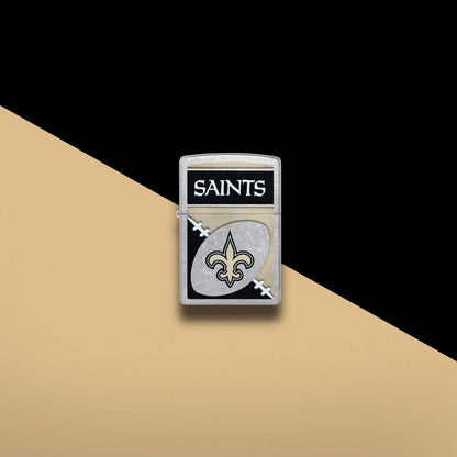 Lifestyle image of Zippo NFL New Orleans Saints Street Chrome Windproof Lighter set on a light gold and black background.