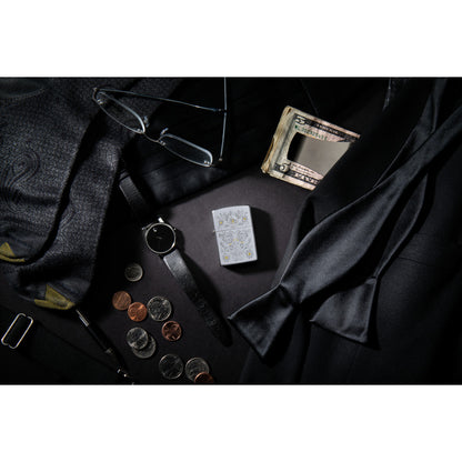 Lifestyle image of Painted Floral Satin Chrome Windproof Lighter laying with items such as money, a watch, ties, glasses, and coins.
