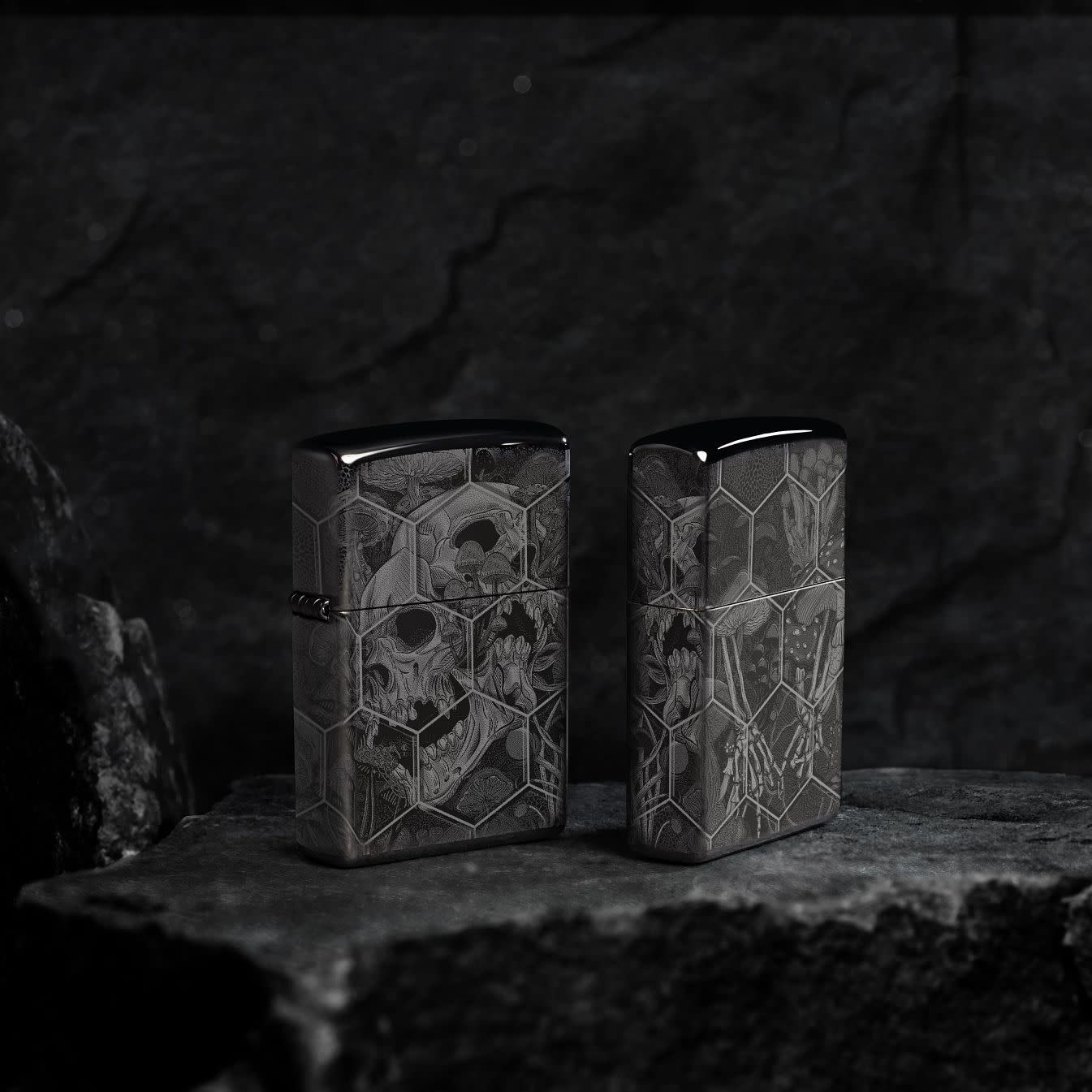 Lifestyle image of two Zippo Mushroom Skulls Design High Polish Black Windproof Lighters, one showing the front of the lighter and the other showing the back at an angle, standing on a dark surface.