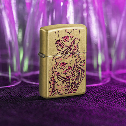 Lifestyle images of Zippo Bony Embrace Design Street Brass Windproof Lighter standing in front of drinking glasses under a blacklight showing the front and hinge side of the lighter. 

