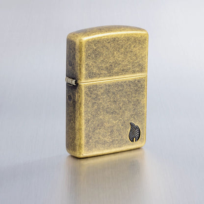 Lifestyle image of Zippo Armor® Series Flame Antique Brass Windproof Lighter on a light gray background.