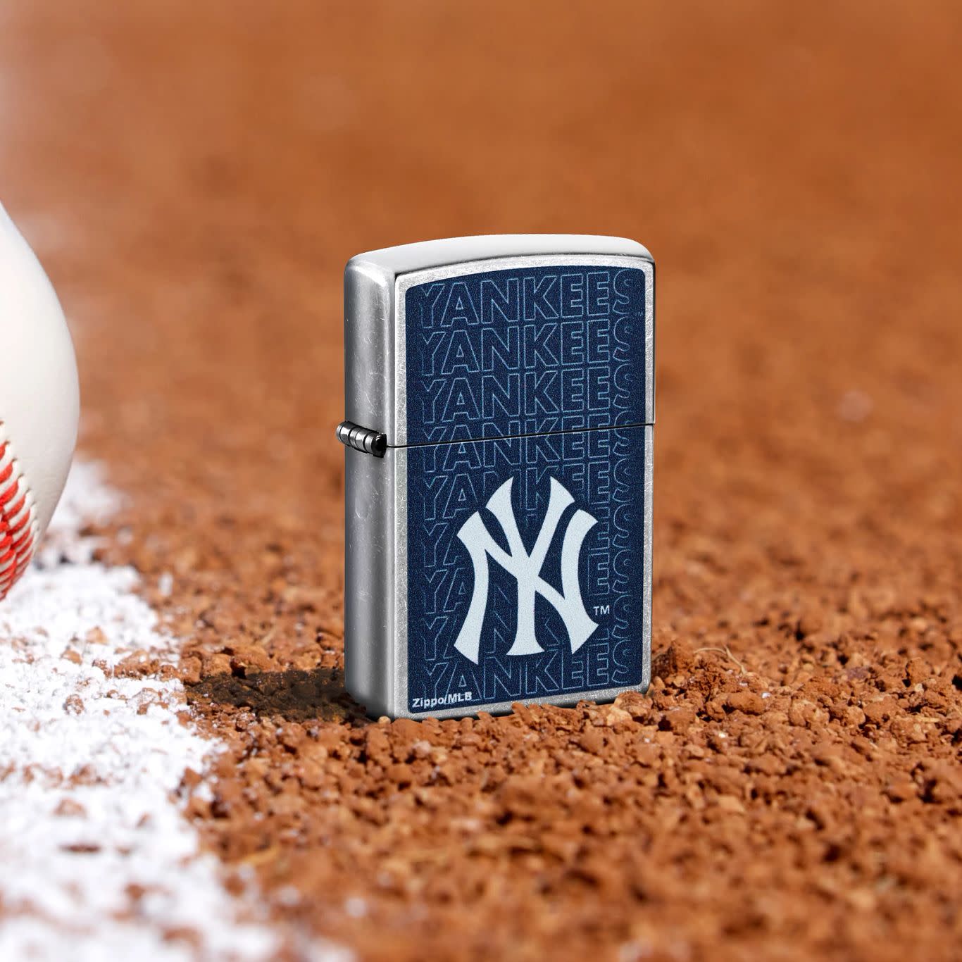 Lifestyle image of Zippo MLB® New York Yankees Street Chrome Windproof Lighter standing in the dirt on a baseball field.