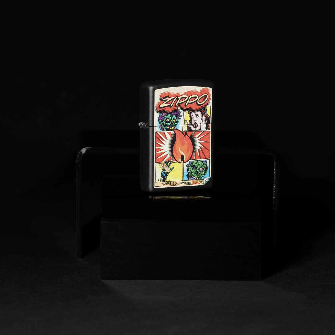 Lifestyle image of Zippo Comic Zombies Design Black Matte Windproof Lighter standing in the dark.