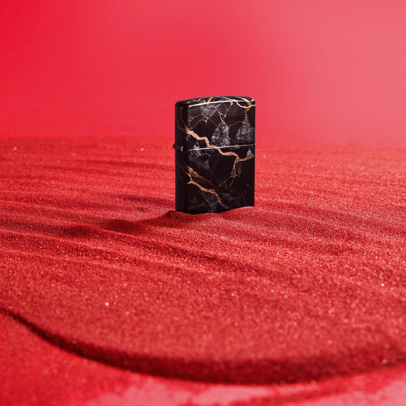 Lifestyle image of Zippo Fusion Marble Design 540 Tumbled Chrome Windproof Lighter standing in red sand.