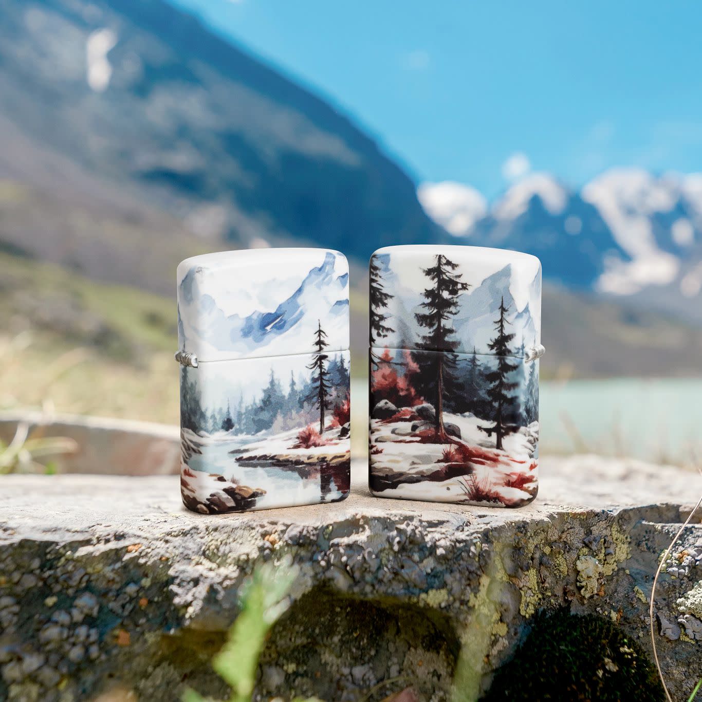 Lifestyle image of two Zippo Frozen Valley Design 540 Matte Windproof Lighters standing on a rock with mountains in the background.