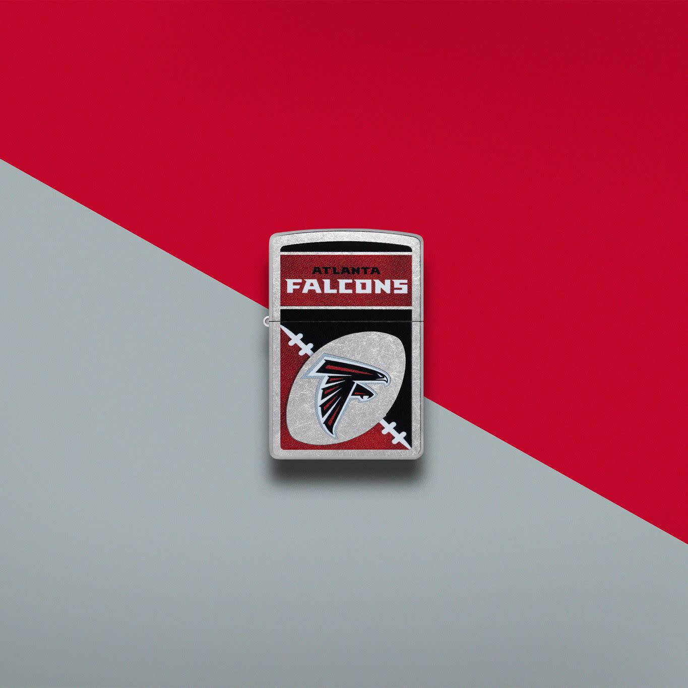 Lifestyle image of Zippo NFL Atlanta Falcons Street Chrome Windproof Lighter set on a red and gray background.