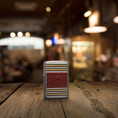Lifestyle image of Zippo Woodgrain Design Pipe Lighter Brushed Chrome Windproof Lighter standing on an old wooden table showing the front of the lighter with an out of focus bar as the background. 

