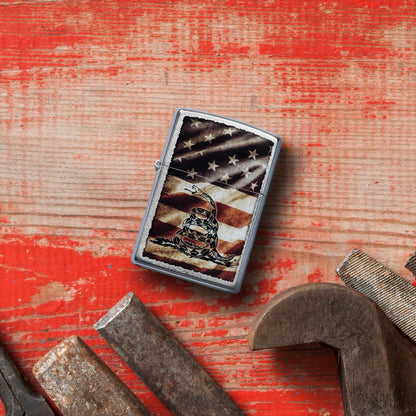 Lifestyle image of Zippo Dont Tread on Me® Street Chrome Windproof Lighter laying on worn red painted wood with tools laying below.