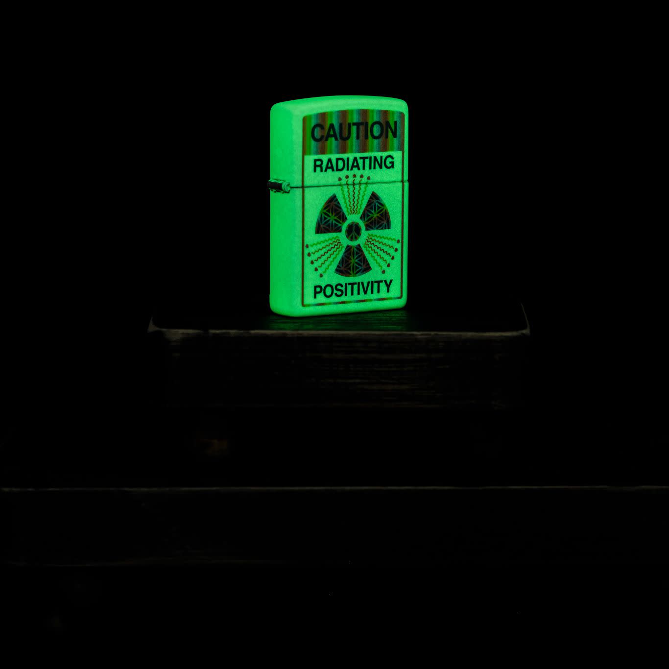 Lifestyle image of Zippo Glowing Positivity Design Glow in the Dark Windproof Lighter glowing in the dark.