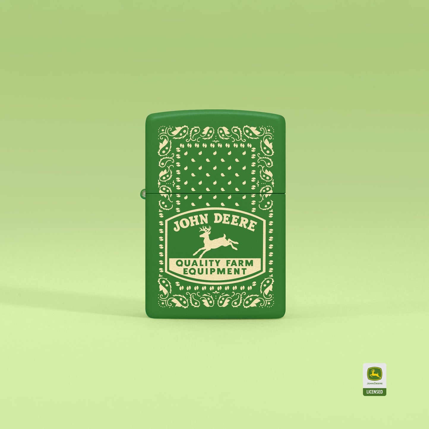 Lifestyle image of Zippo John Deere Paisley Design Moss Green Windproof Lighter standing with a light green background.

