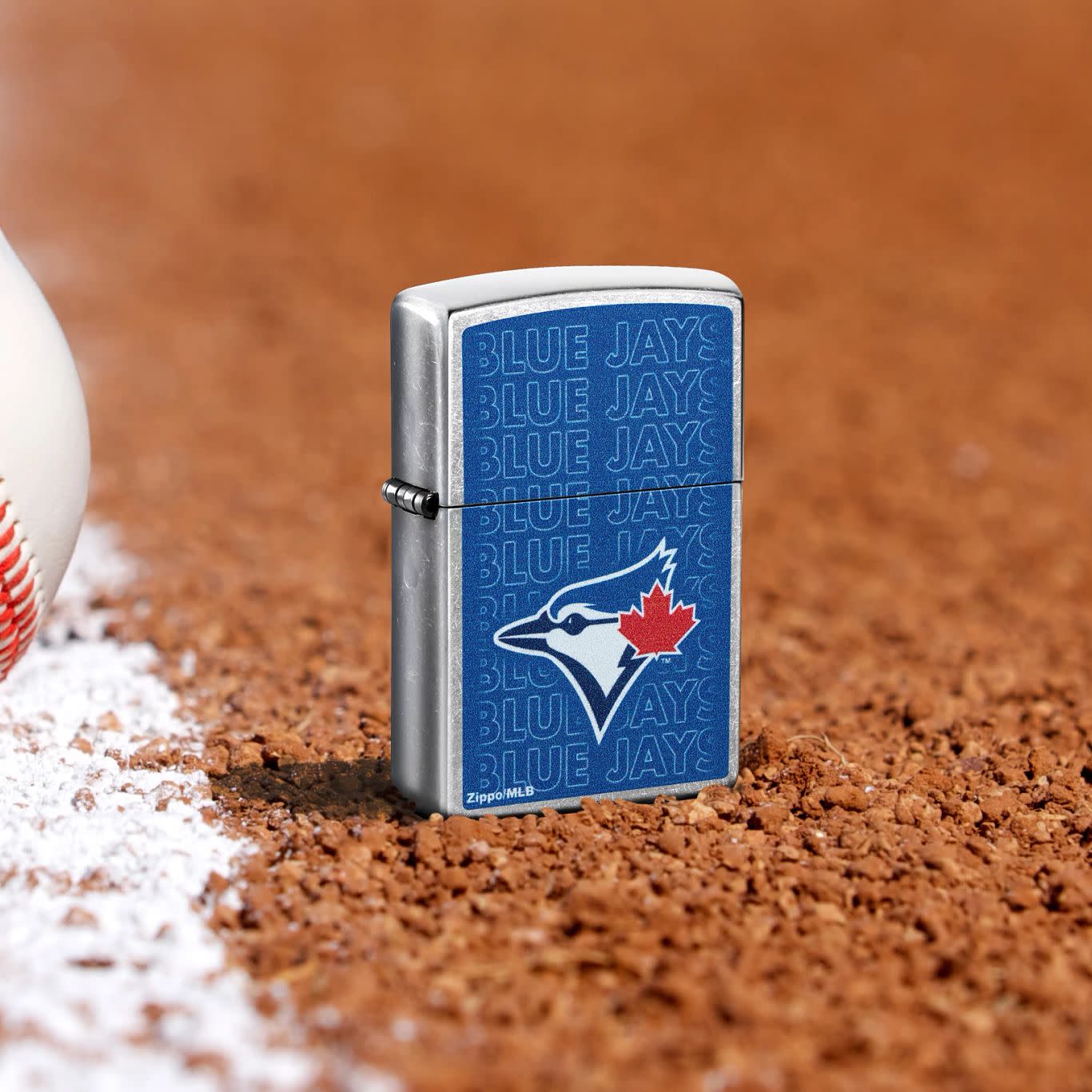 Lifestyle image of Zippo MLB® Toronto Blue Jays Street Chrome Windproof Lighter standing in the dirt on a baseball field.