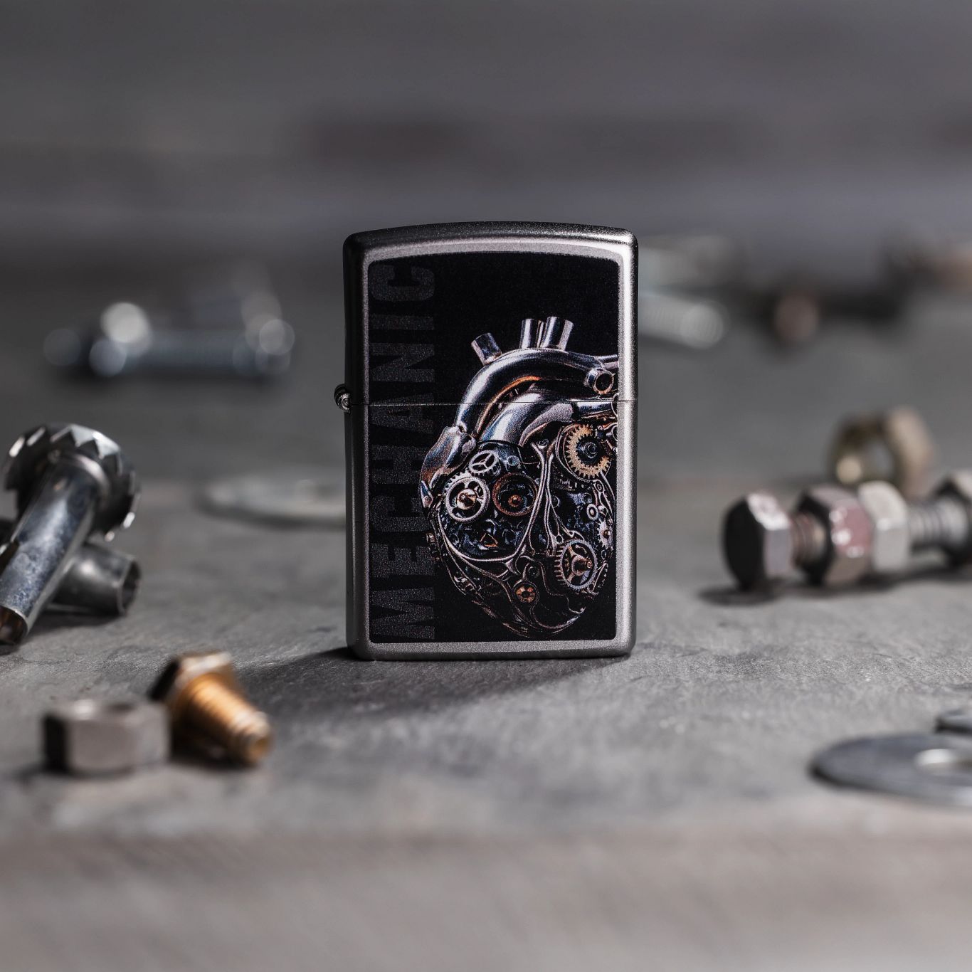 Lifestyle image of Zippo Mechanical Heart Design Satin Chrome Windproof Lighter standing on concrete with nuts and bolts.

