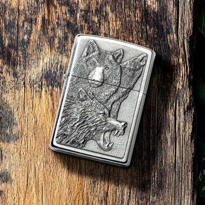 Lifestyle image of Zippo Wolf Pack Emblem Brushed Chrome Windproof Lighter lying on a plank of old weathered wood, showing the front of the lighter. 

