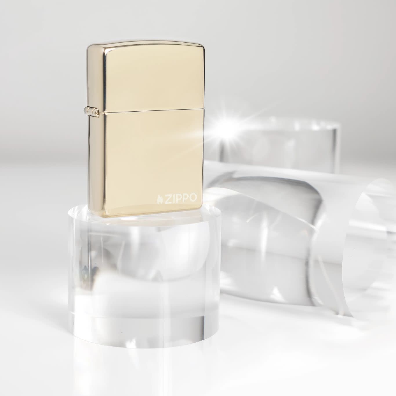 Lifestyle image of Zippo Classic Champagne Zippo Logo Windproof Lighter standing on a clear cylinder with two cylinders in the background.