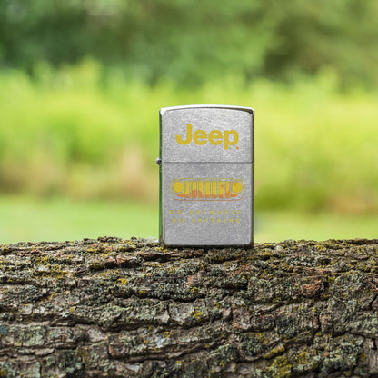 Lifestyle image of Zippo Jeep® Grille Design Street Chrome Windproof Lighter standing on a tree trunk with an overgrown field in the background.

