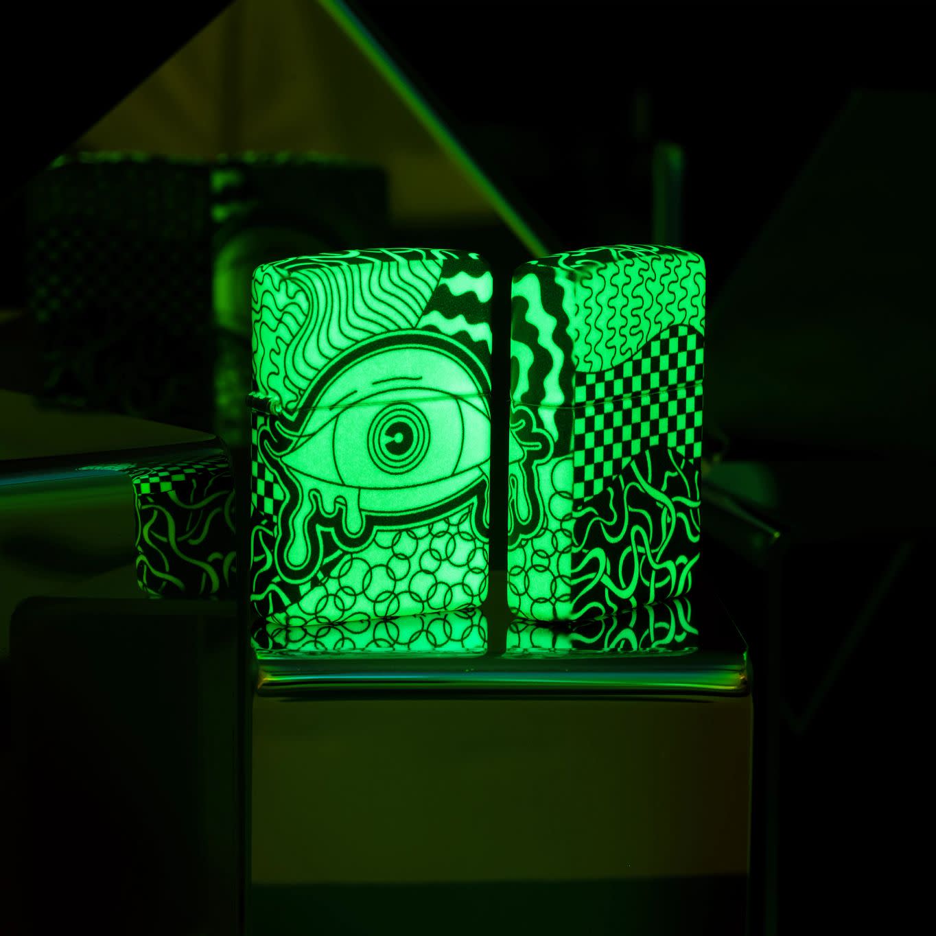 Lifestyle image of two Zippo Vision Test Design Glow in the Dark Windproof Lighters glowing in the dark.