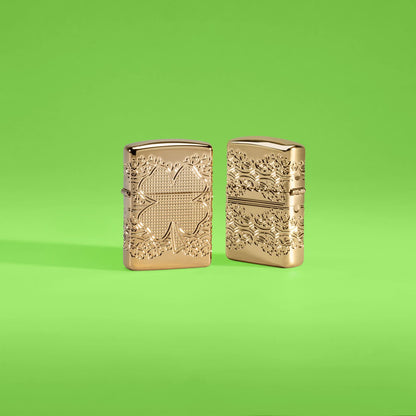 Lifestyle image of two Zippo Lucky Clover Design Armor® High Polish Gold Plate Windproof Lighters in a lime green scene, one showing the front of the lighter and the other showing the back.