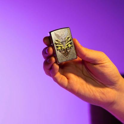 Lifestyle image of Zippo Phoenix Tree Design Street Chrome Windproof Lighter closed in hand showing the front of the lighter with a purple ombre background. 

