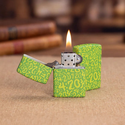 Lifestyle image of two Zippo 420 Clouds Design 540 Matte Windproof Lighters standing one a tan placemat on a table in front of 2 books. One open and lit showing the front of the lighter while the other is closed and showing the back of the lighter. 

