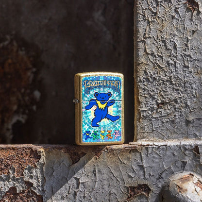 Lifestyle image of Zippo Grateful Dead Dancing Bears Design Street Brass Windproof Lighter standing on a rusty painted steel structure showing the front of the lighter. 

