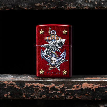 Lifestyle image of Zippo Rietveld Anchor Design Candy Apple Red Windproof Lighter standing in the gap of a gate showing the front of the lighter. 


