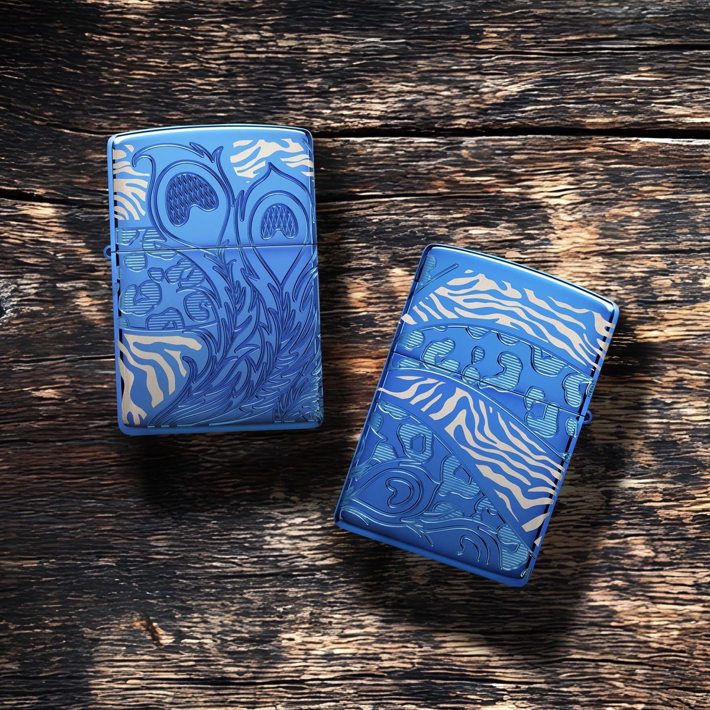 Lifestyle image of two Zippo Animal Flair Design Armor® High Polish Blue Windproof Lighters lying on a plank of old weathered wood. One showing the front of the lighter while the other is showing the back of the lighter. 

