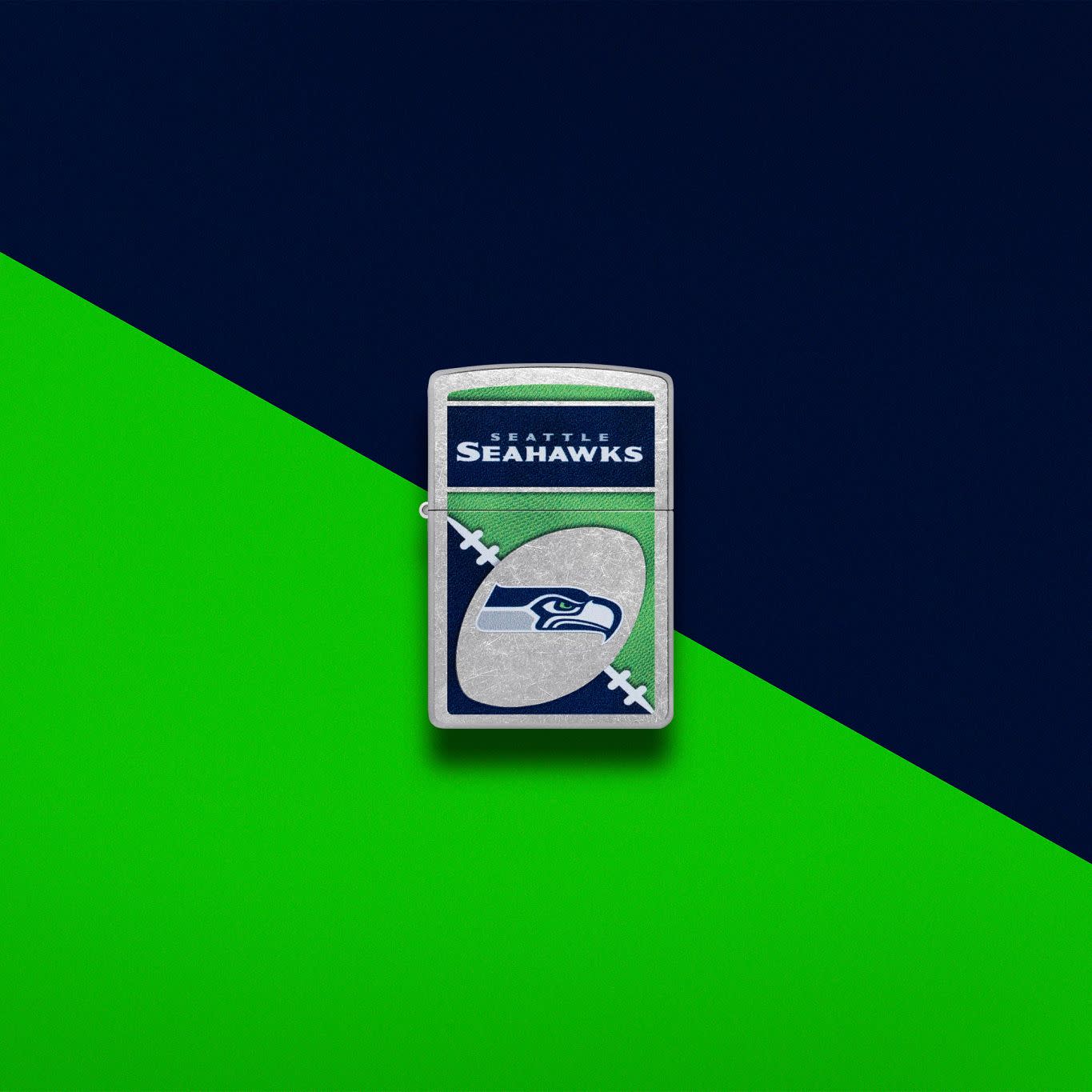 Lifestyle image of Zippo NFL Seattle Seahawks Street Chrome Windproof Lighter set on a green and dark blue background.