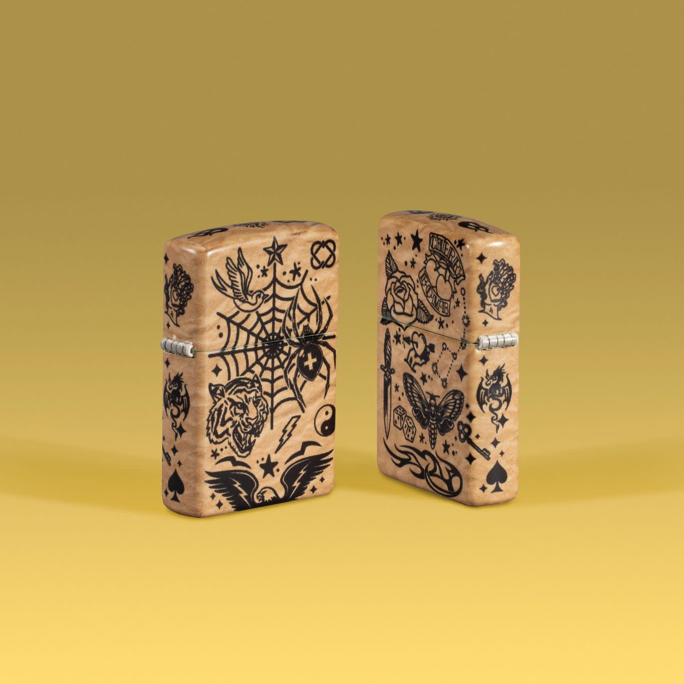 Lifestyle image of two Zippo Flash Tattoo 540 Matte Windproof Lighters on a yellow ombre background.