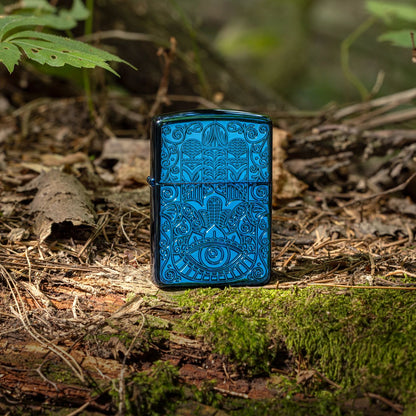 Lifestyle image of Zippo Hamsa Design Armor® High Polish Blue Windproof Lighter standing on a mossy ground, covered in seasoned foliage and twigs with a touch of greenery.

