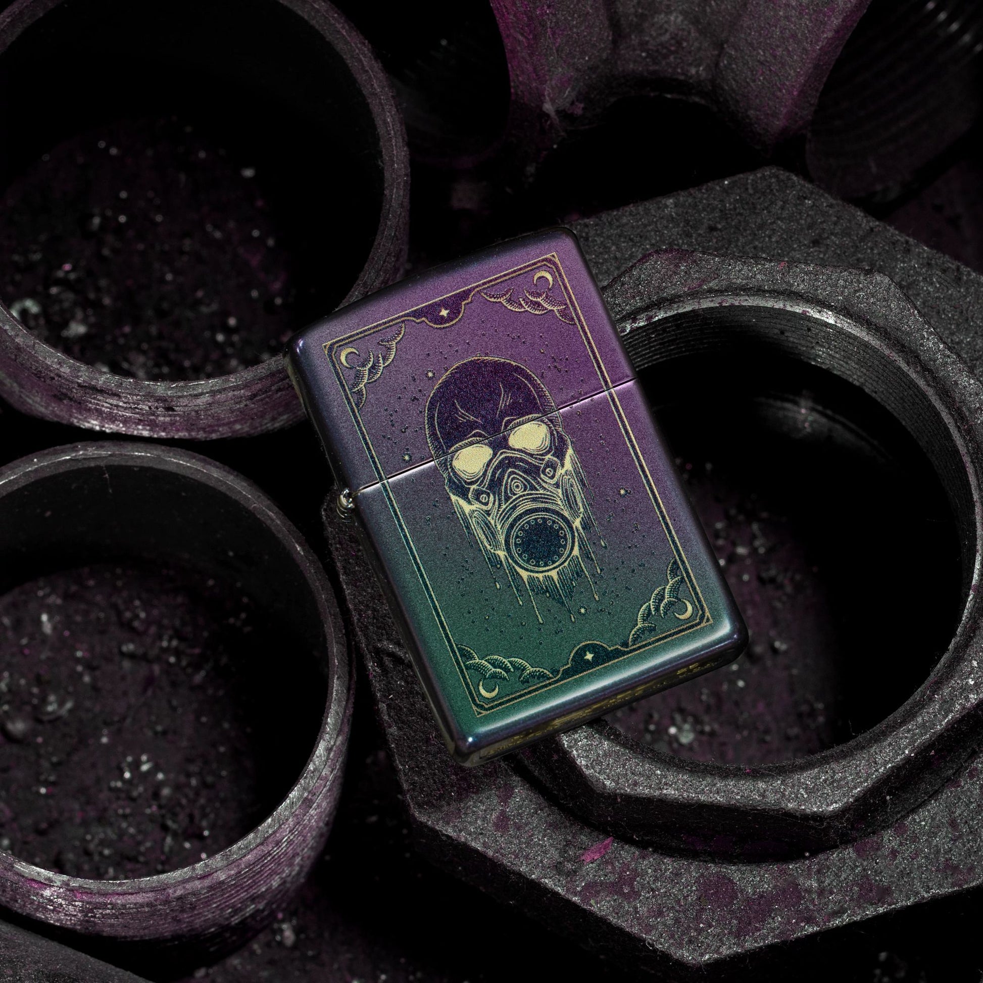 Lifestyle image of Zippo Gas Mask Design Iridescent Windproof Lighter lying flat on a few metal couplings, showing the front of the lighter. 


