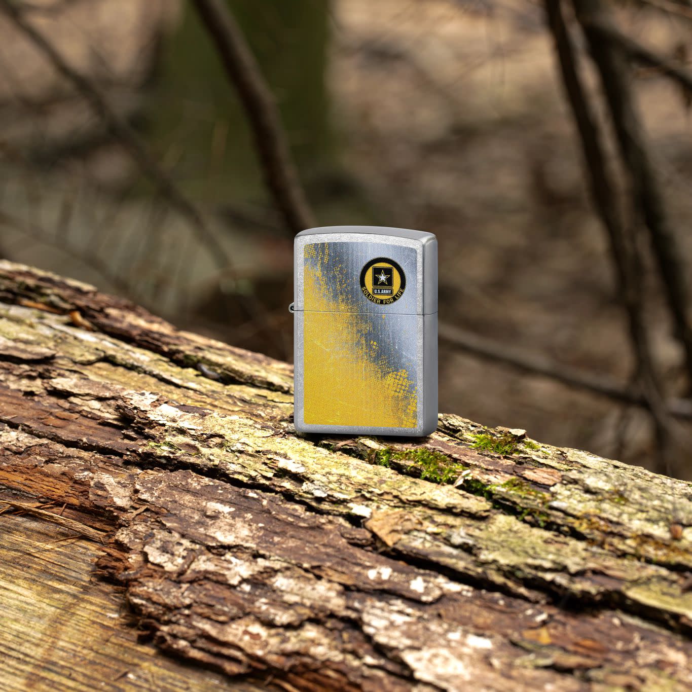 Lifestyle image of Zippo U.S. Army® Soldier for Life Street Chrome Windproof Lighter standing on a log with branches in the background.