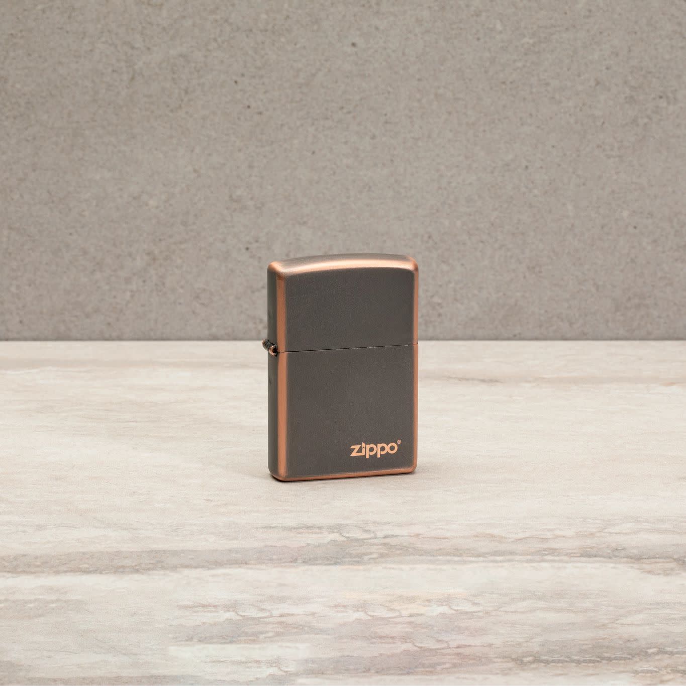 Lifestyle image of Classic Rustic Bronze Zippo Logo Windproof Lighter standing on a countertop.