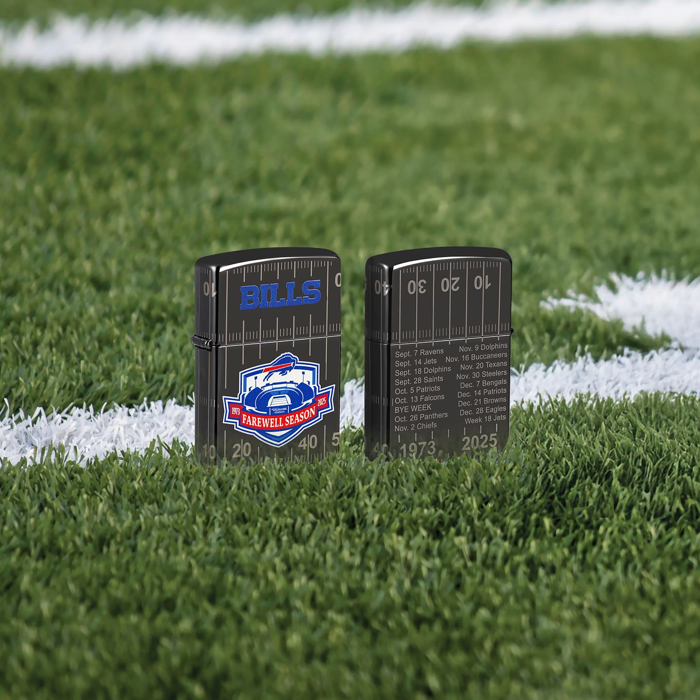 Lifestyle image of two Zippo Buffalo Bills Farewell Season Design High Polish Black Windproof Lighters; one showing the front of the lighter and the other showing the back of the lighter, both standing on a football field.  

